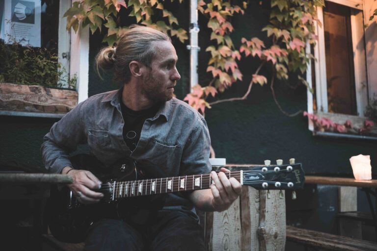 musicien joue guitare éléctrique devant un bar